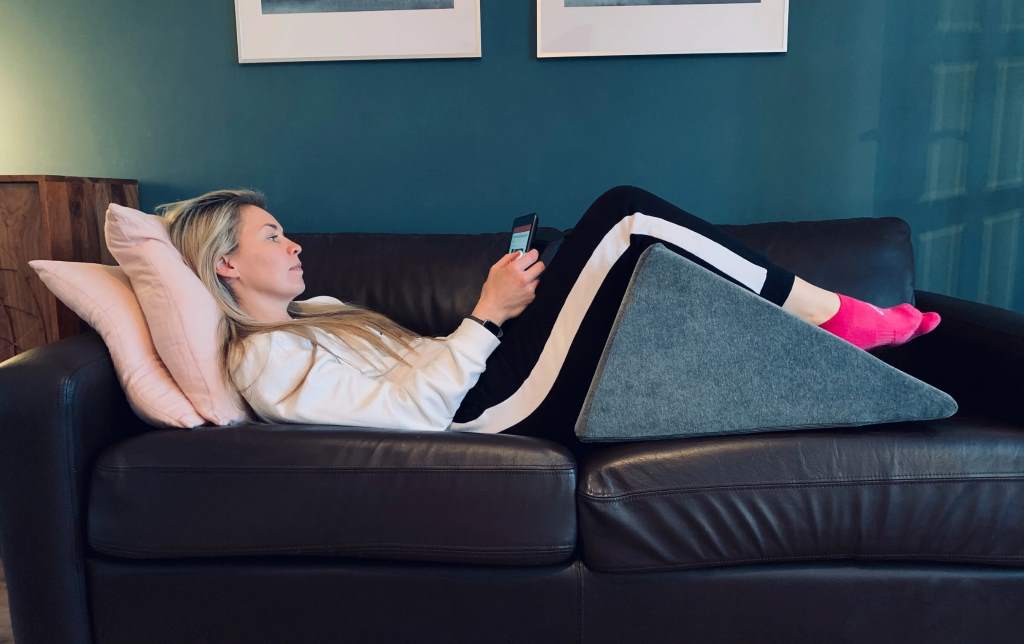 Side sleeper using knee and torso wedge set for lower back pain and sciatica relief